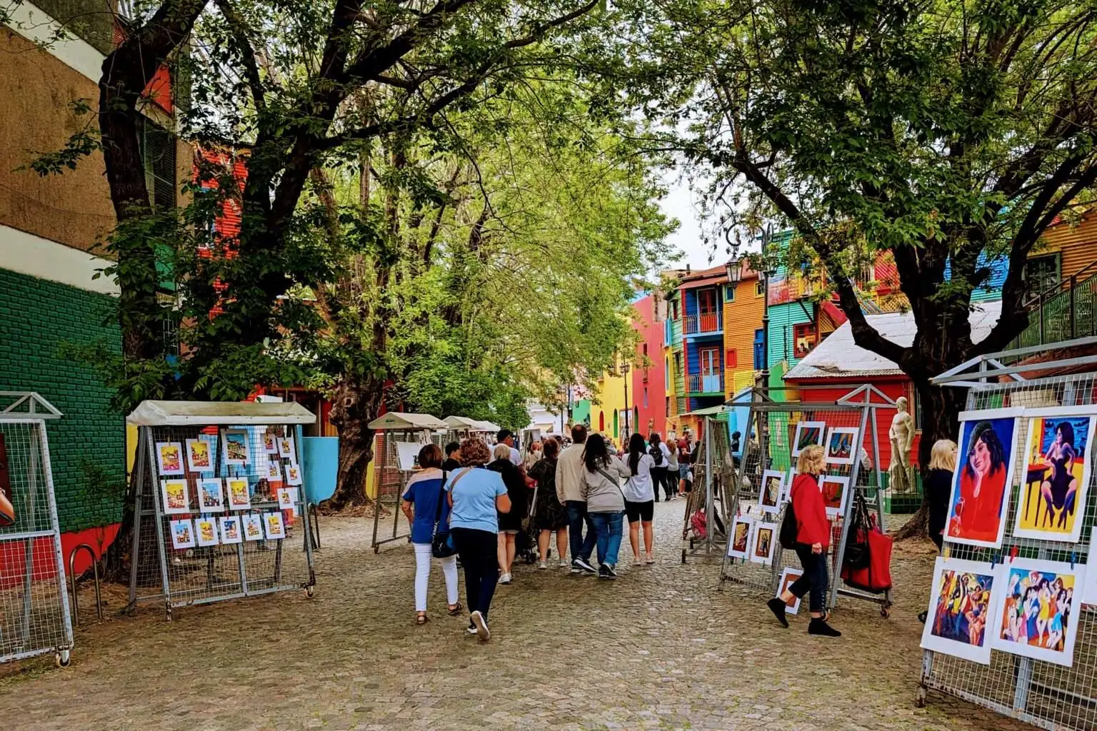 A pedestrian walkway with colorful buildings on either side and artists displaying artwork - Free Buenos Aires Walking Tours