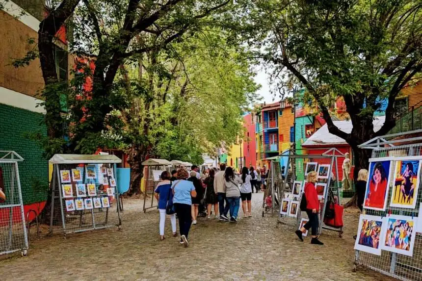 A pedestrian walkway with colorful buildings on either side and artists displaying artwork - Free Buenos Aires Walking Tours
