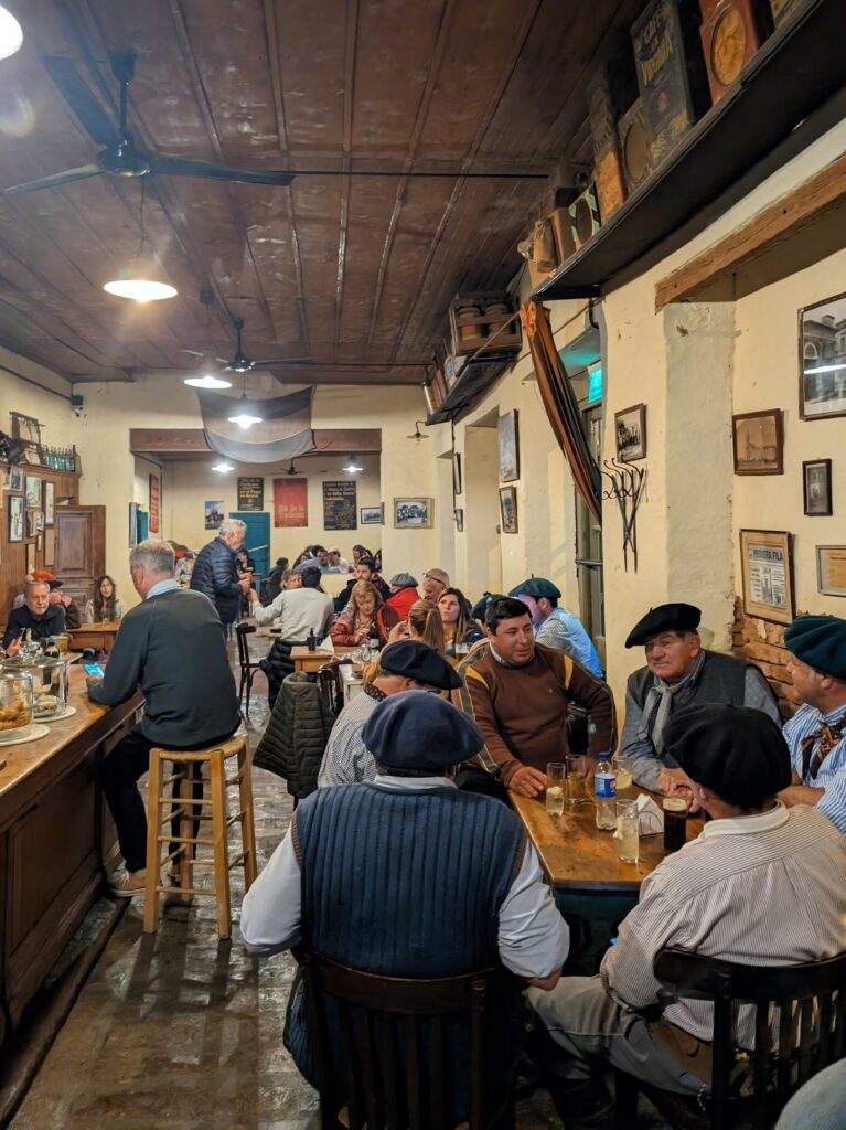 A bustling restaurant filled with people seated at tables, enjoying good company and delicious meals - San Antonio de Areco