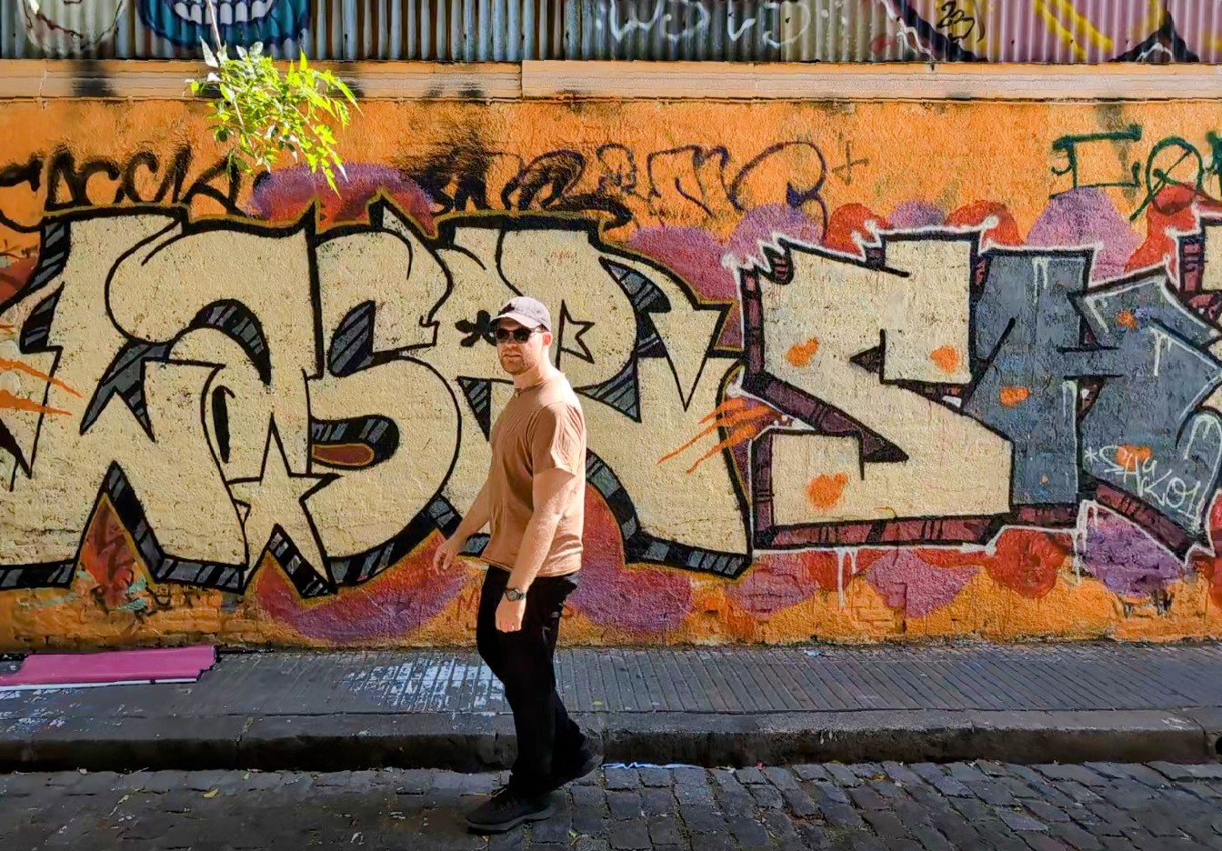 Man standing in front of an orange and pink mural in Palermo Soho, Buenos Aires, Argentina while traveling
