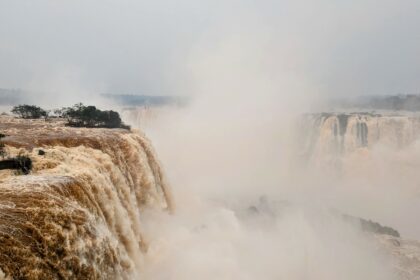 A large waterfall with orange water flowing down - Iguazu falls from Brazil side