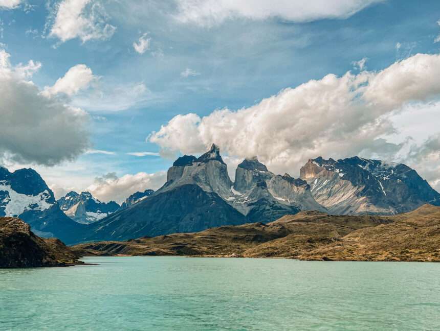 A beautiful mountain range behind a body of turquoise water - Torres del Paine W Trek