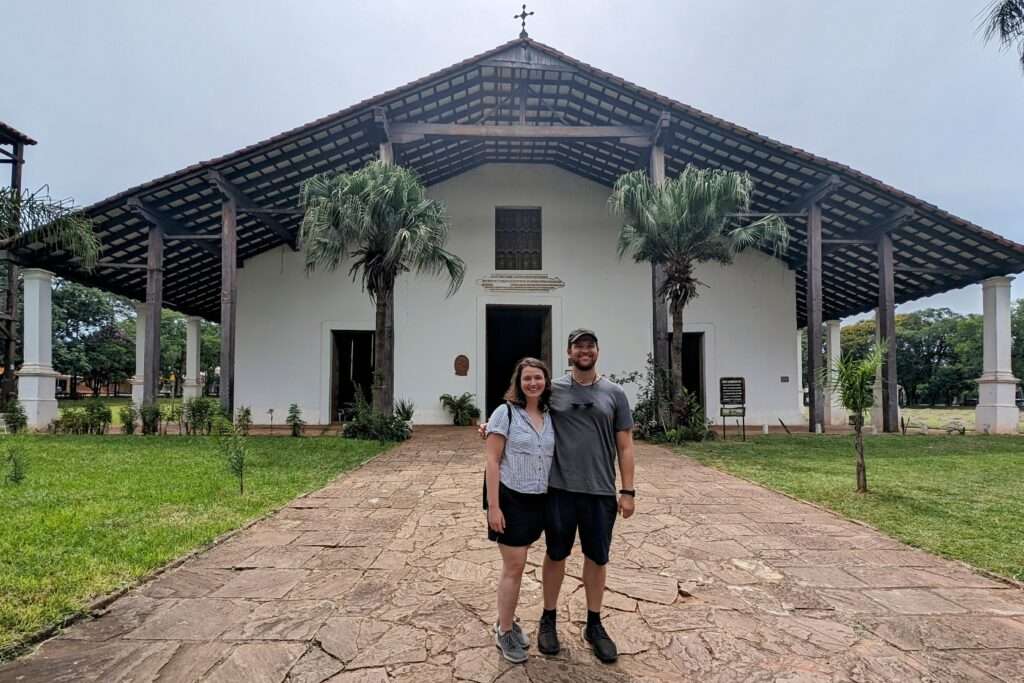 Standing in front of the Templo de San Buenaventura, a wooden church that is part of the Circuito de Oro in Paraguay