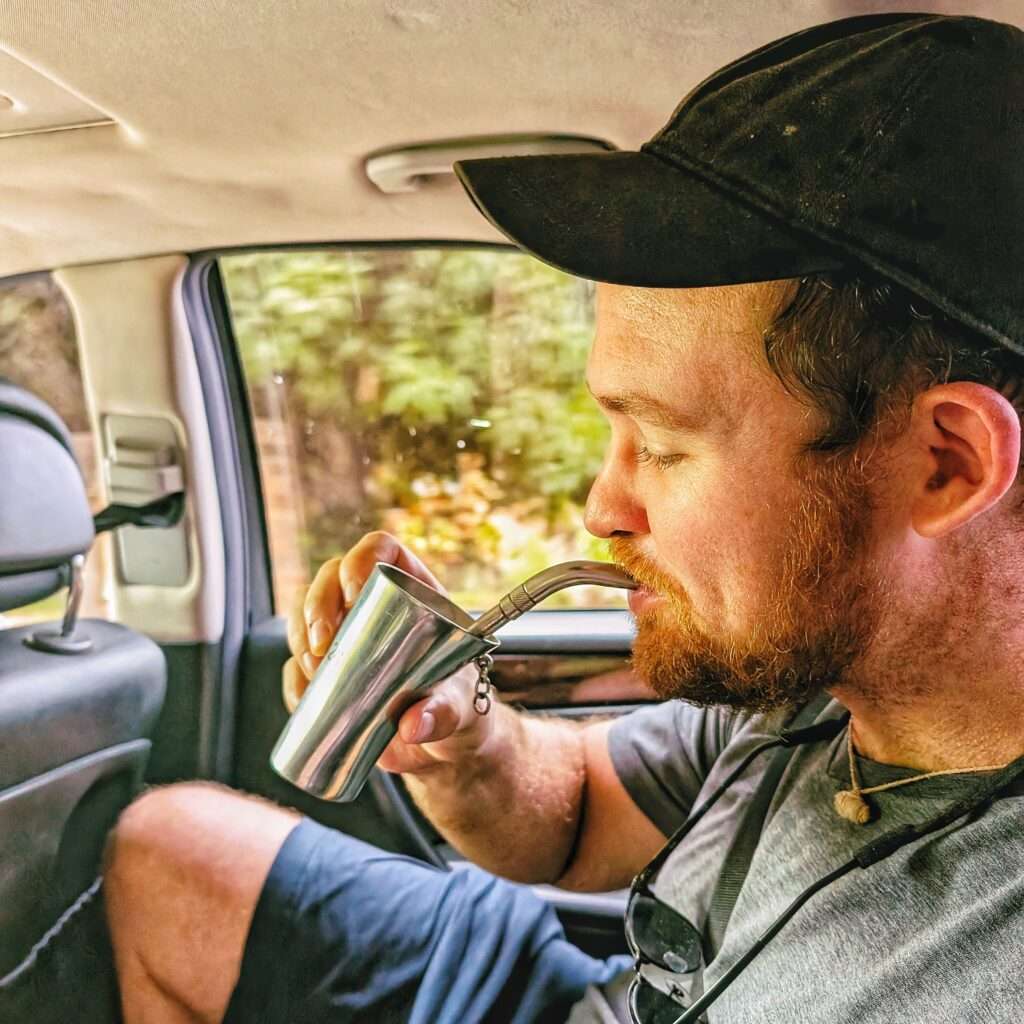A man drinking out of a metal straw and cup (terere)