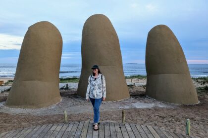 A woman standing in front of a large sculpture of someone's hands coming out of the ground - Things to do in Punta del Este