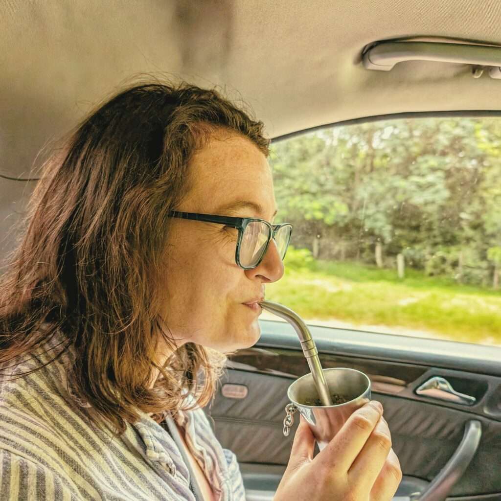 A woman drinking out of a metal straw and cup (terere)