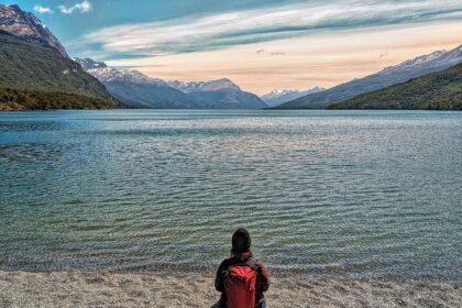 A person sitting on the beach of a lake at sunrise - Tierra del Fuego National Park