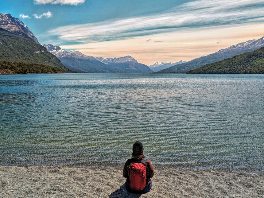 A person sitting on the beach of a lake at sunrise - Tierra del Fuego National Park