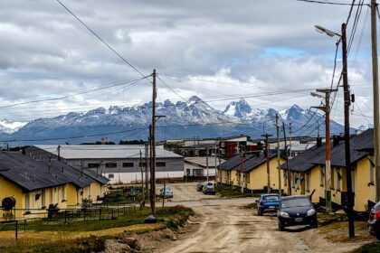 A dirt road going through town with large mountains in the background - best things to do in Ushuaia