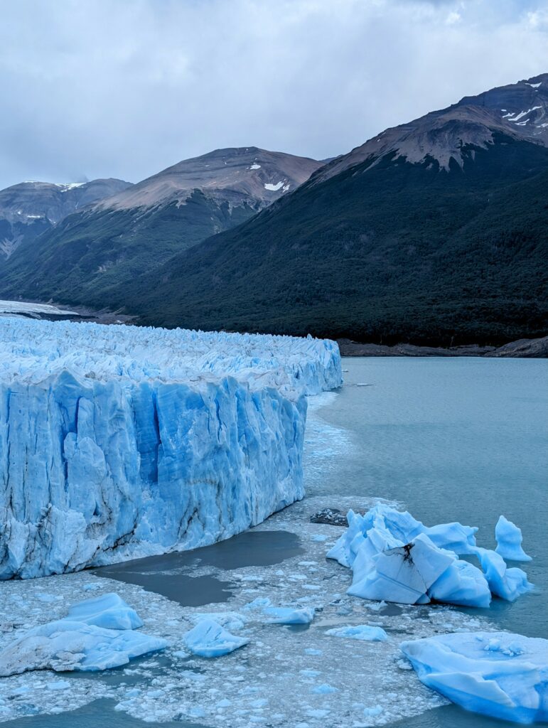 A gigantic glacier with glistening blue ice fragments scattered across its vast expanse