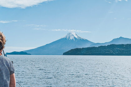 A person on a boat on a lake in front of volcanos and mountains - Cruce Andino