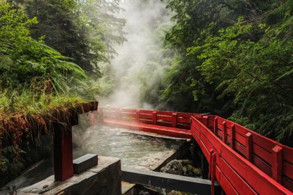 A red walkway going over steamy water through a forest - Villarica and Puerto Varas