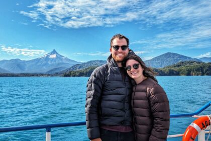 Two people on a boat on a lake in front of volcanos and mountains - Cruce Andino