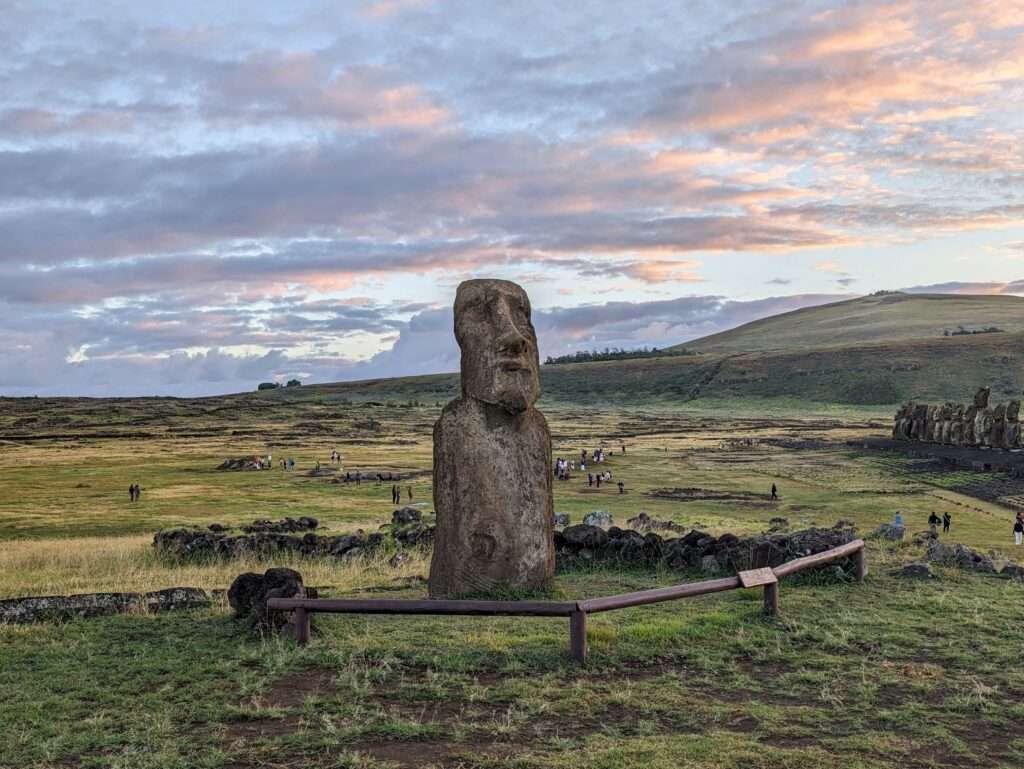 An enormous head statues on a hill with the sun rising in the background - Easter Island itinerary