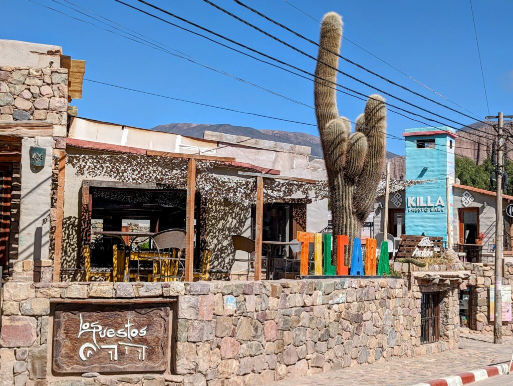 The stone exterior of a restaurant with a cactus in front of it in a town that can be seen when visiting Salta