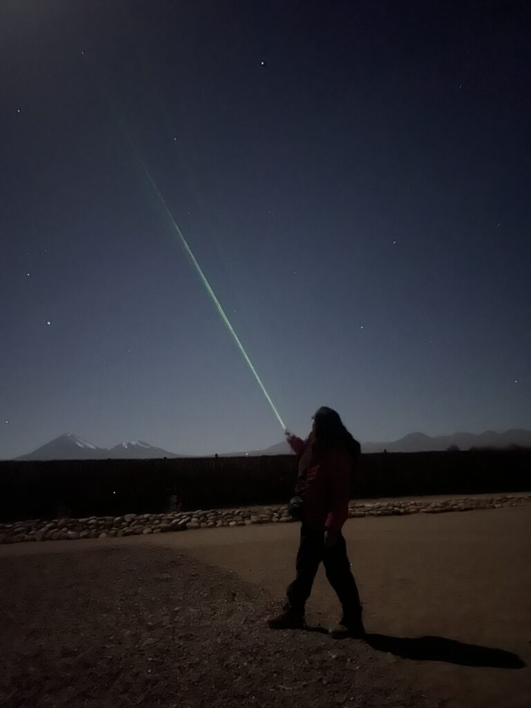 A person pointing a laser pointer in the night sky of the Atacama desert