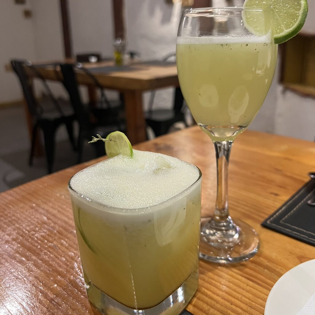 Two yellow cocktails in different glasses in a restaurant