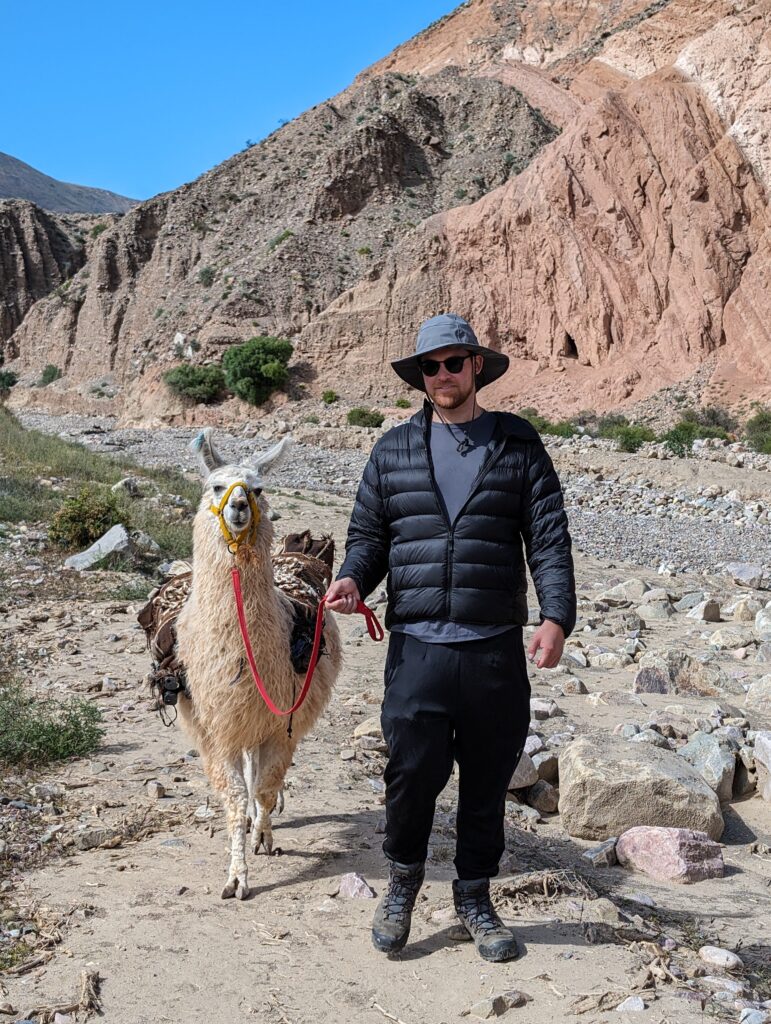 A man holding a llama with a mountain in the background