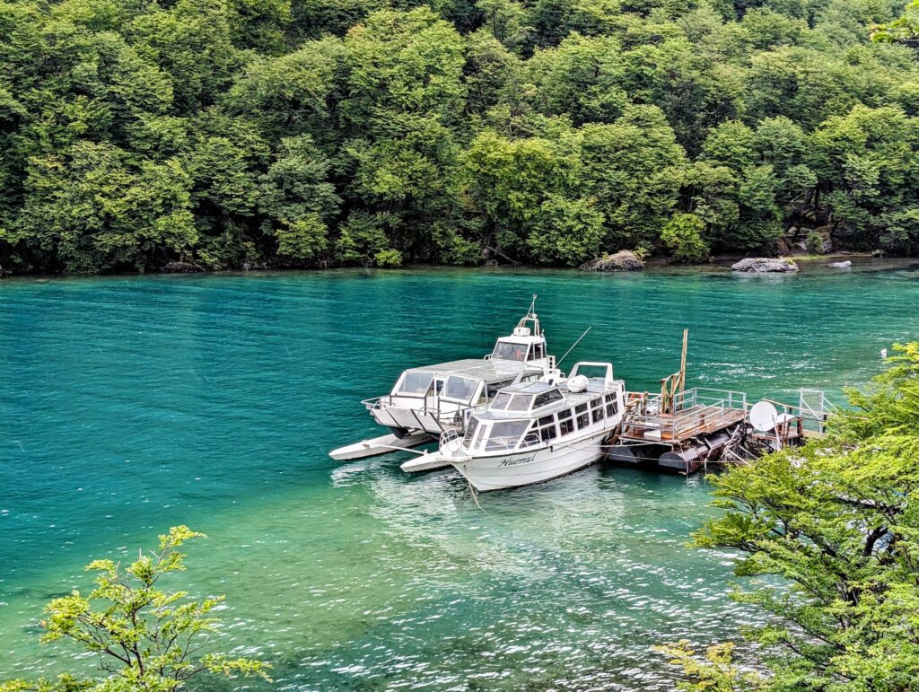 A boat docked on a green lake used to cross the border between Chile and Argentina in Patagonia