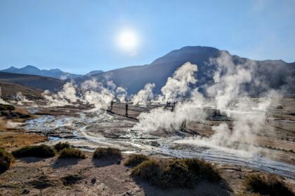 A landscape of geysers with the sun rising over the mountains behind - San Pedro de Atacama desert itinerary