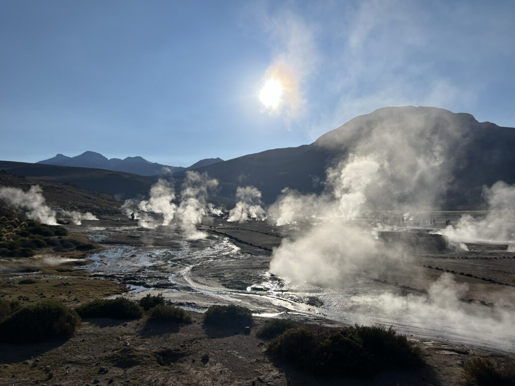 A landscape of geysers in the Atacama desert with water vapor rising from the ground