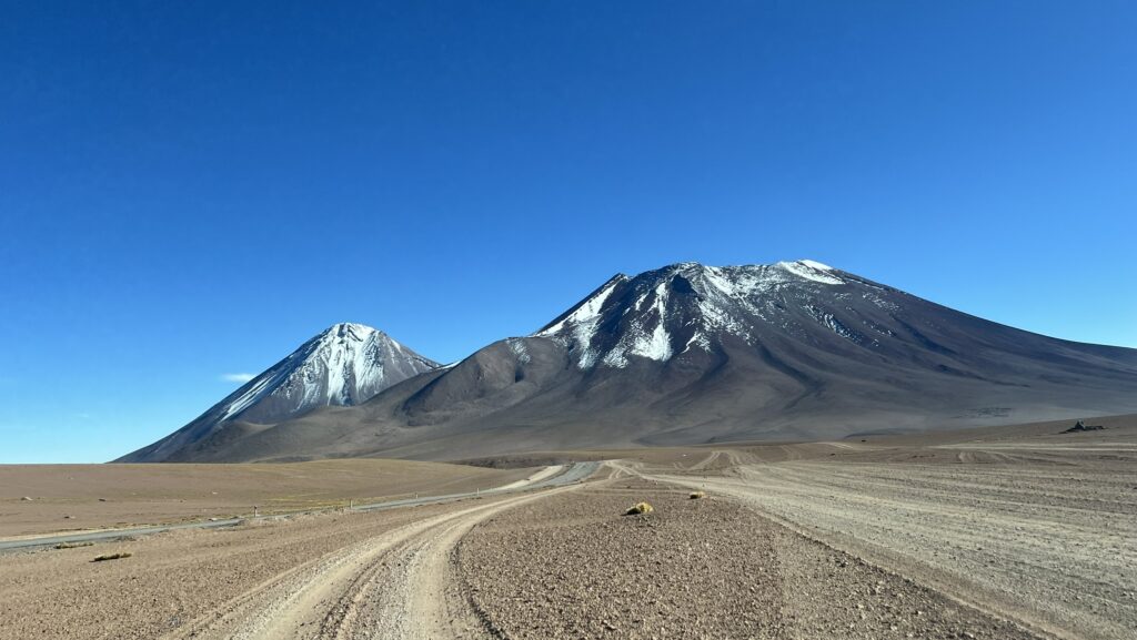 A road heading towards a snow-capped volcano in the Atacama desert