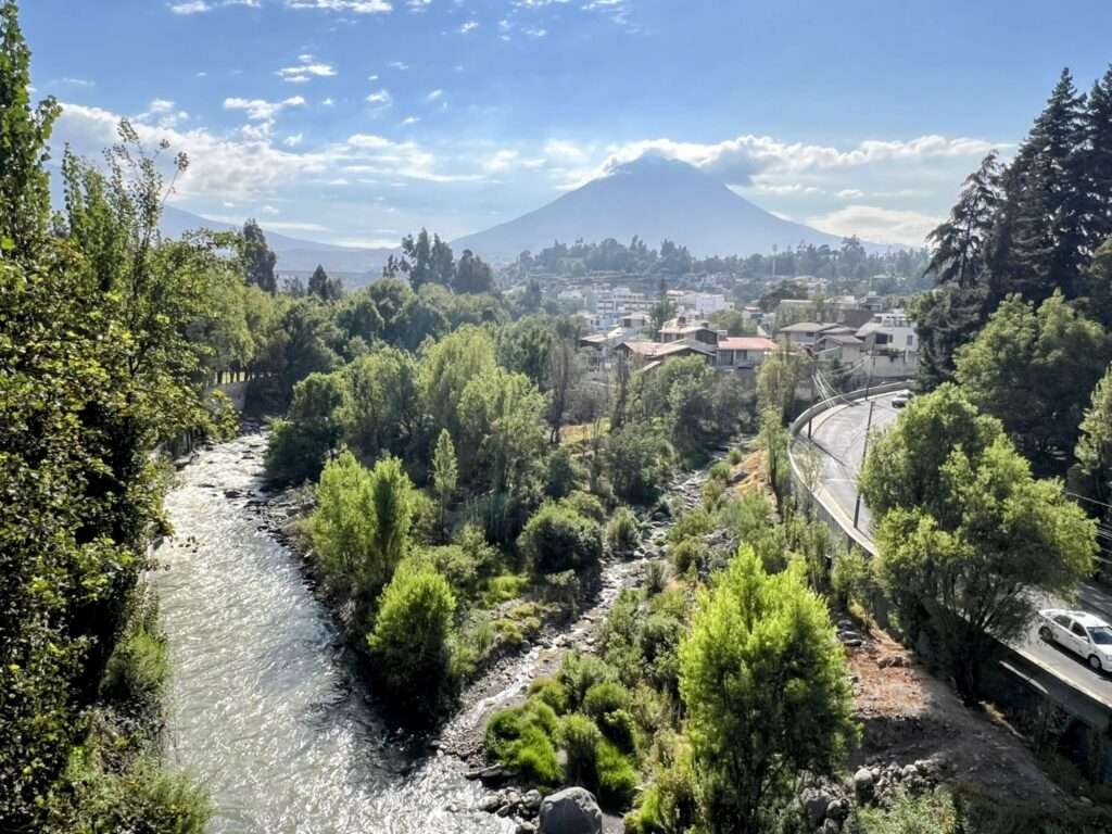 A town and river in front of a volcano in Arequipa