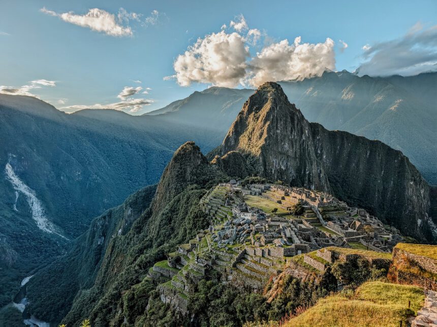 Visiting Machu Picchu with rays of sunshine coming over the mountains at sunset - visited with Alpaca Expeditions, one of the best Inca trail tour operators
