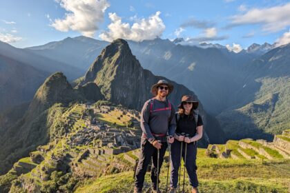 Two people standing in their hiking gear in front of Machu Picchu