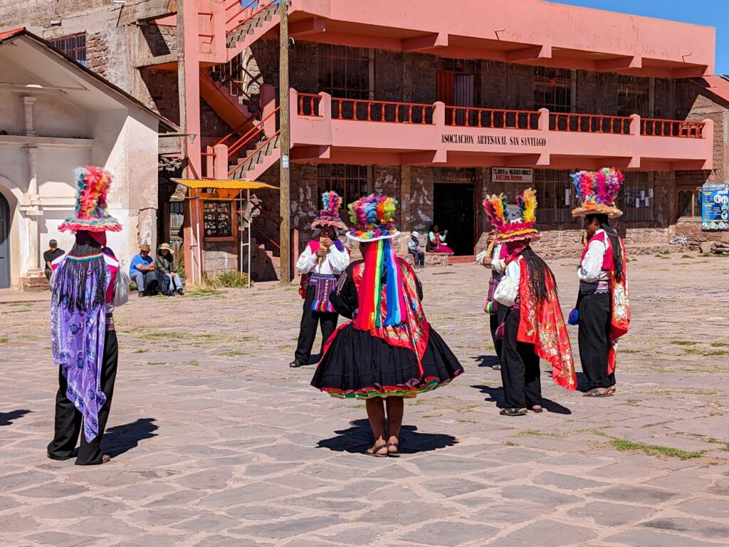 A few people dancing in a courtyard in colorful clothing during a Lake Titicaca homestay tour