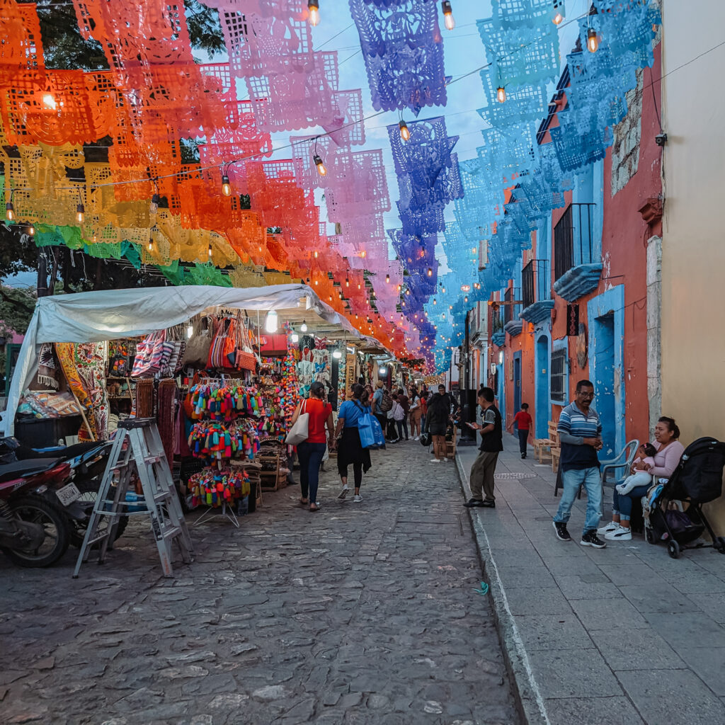 An artisanal market with a rainbow of flags above it as one of the many things to do in Oaxaca