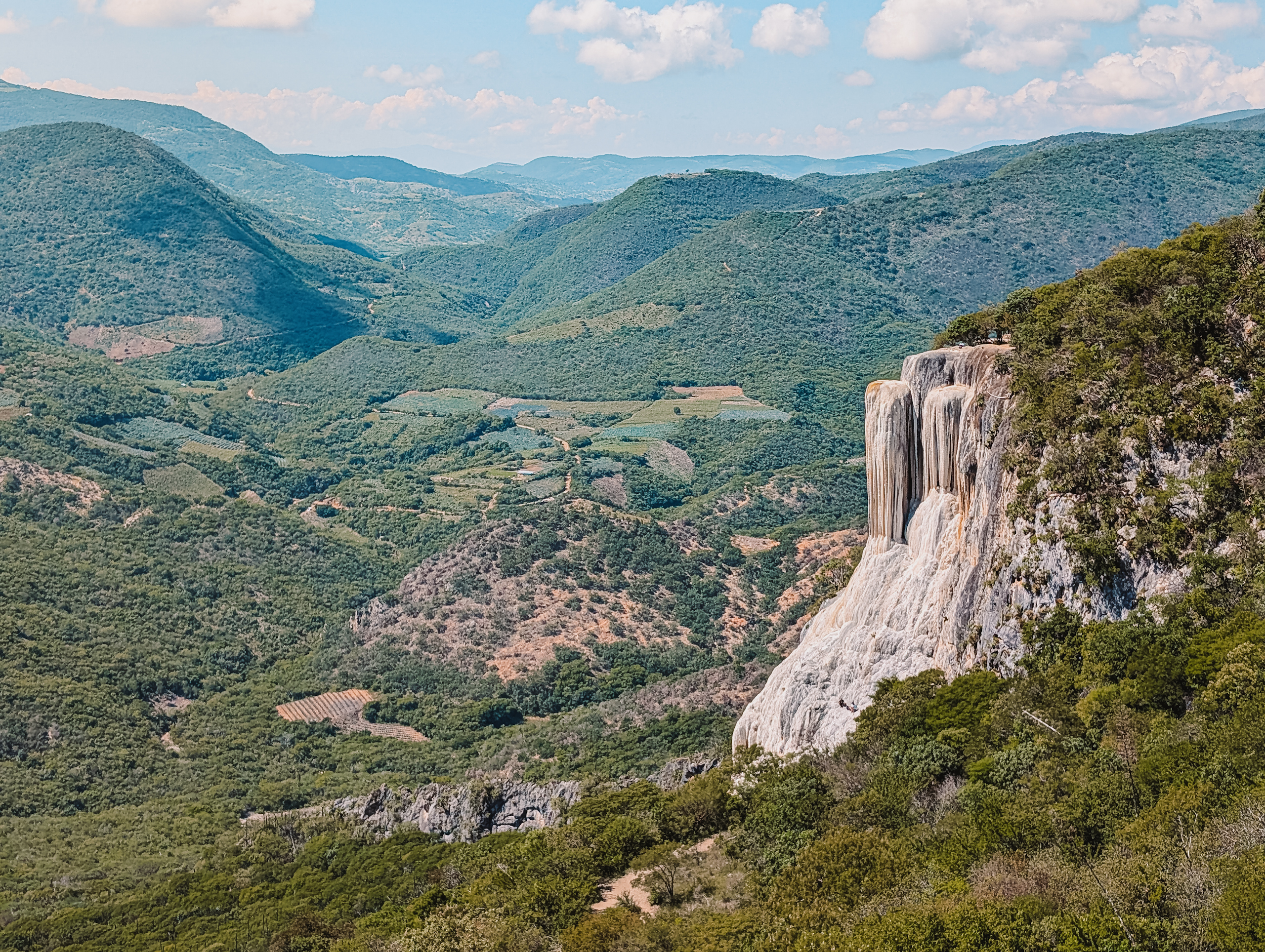 A waterfall that looks frozen as part of Hierve el Agua outside of Oaxaca within a forested hilly landscape