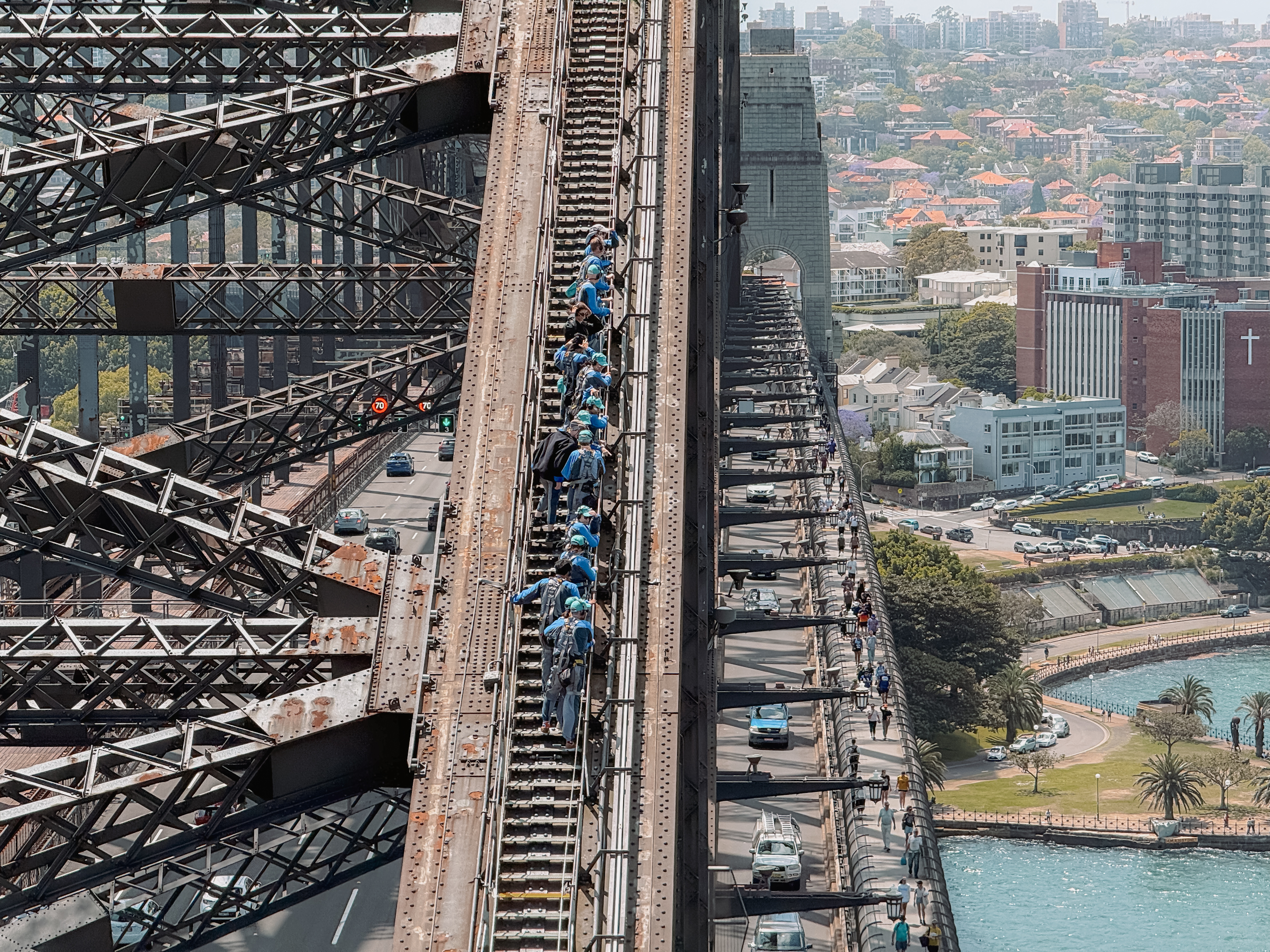 People climbing up and over a bridge over water - top things to do in Sydney