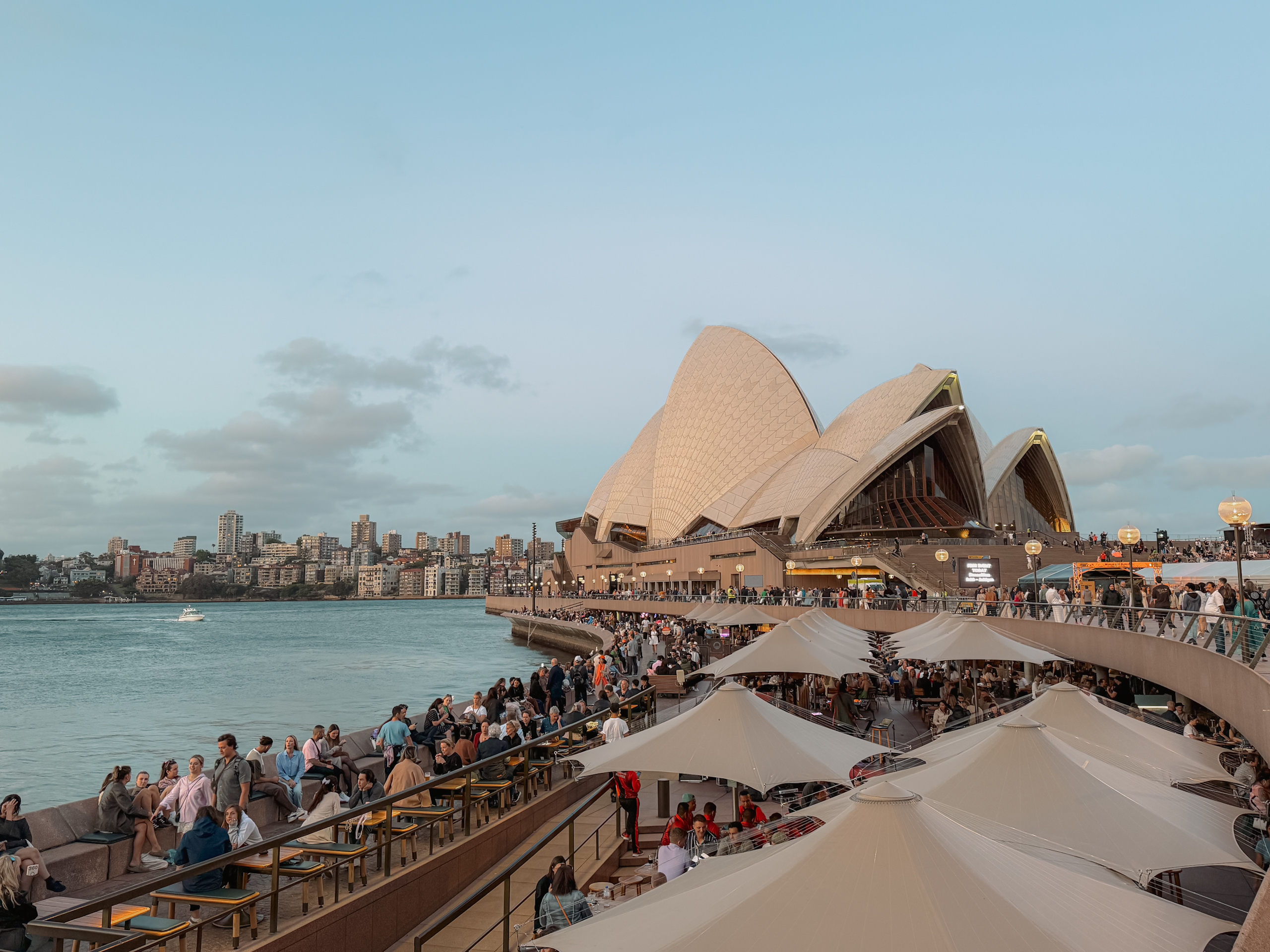 People sitting along the quay in front of the Sydney Opera House - top things to do in Sydney itinerary