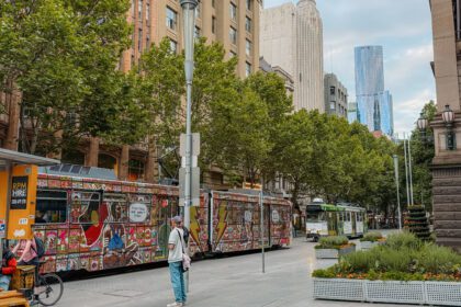 A tram car with art work on it going through the city of Melbourne