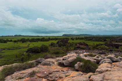 the top of a large rock overlooking a field below - day trips from Darwin