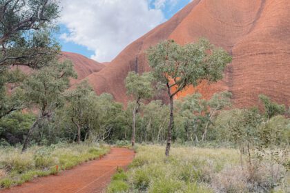 A path leading between low brush to a huge red rock - best time of year to visit uluru