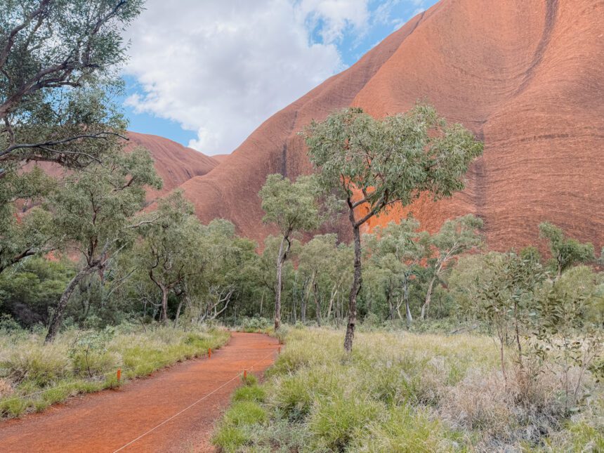 A path leading between low brush to a huge red rock - best time of year to visit uluru