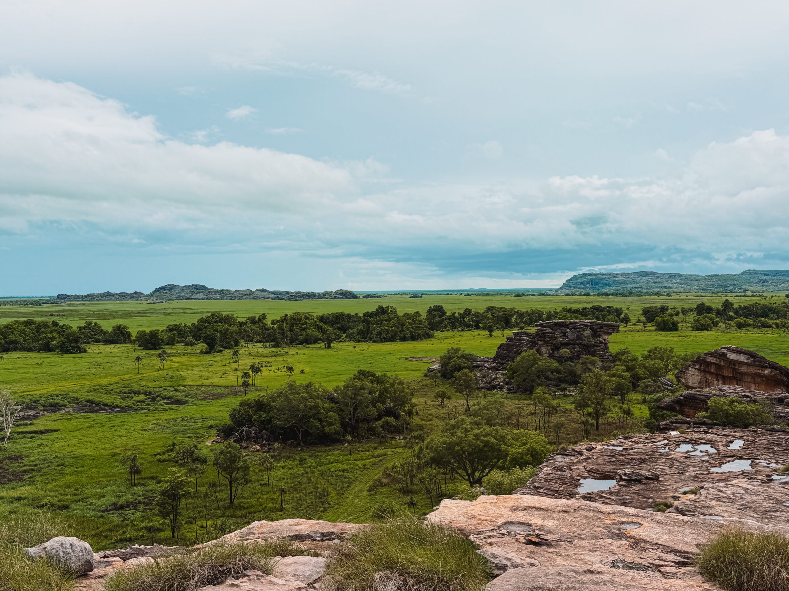 Overlooking a large grassy plain from the top of large red rocks - day trips from Darwin
