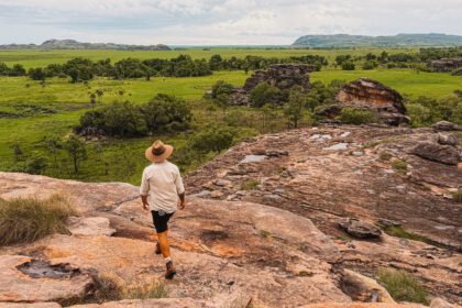the top of a large rock overlooking a field below - Northern Territory tour