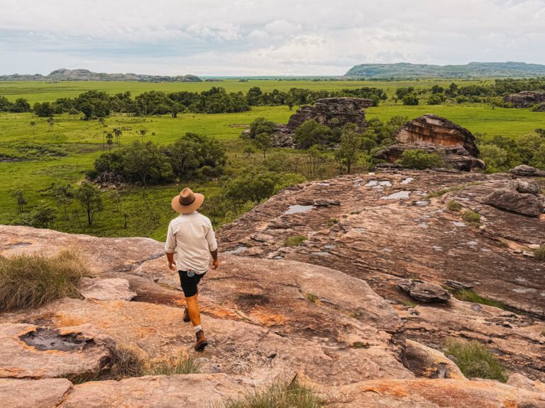 the top of a large rock overlooking a field below - Northern Territory tour