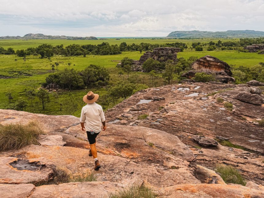 the top of a large rock overlooking a field below - Northern Territory tour
