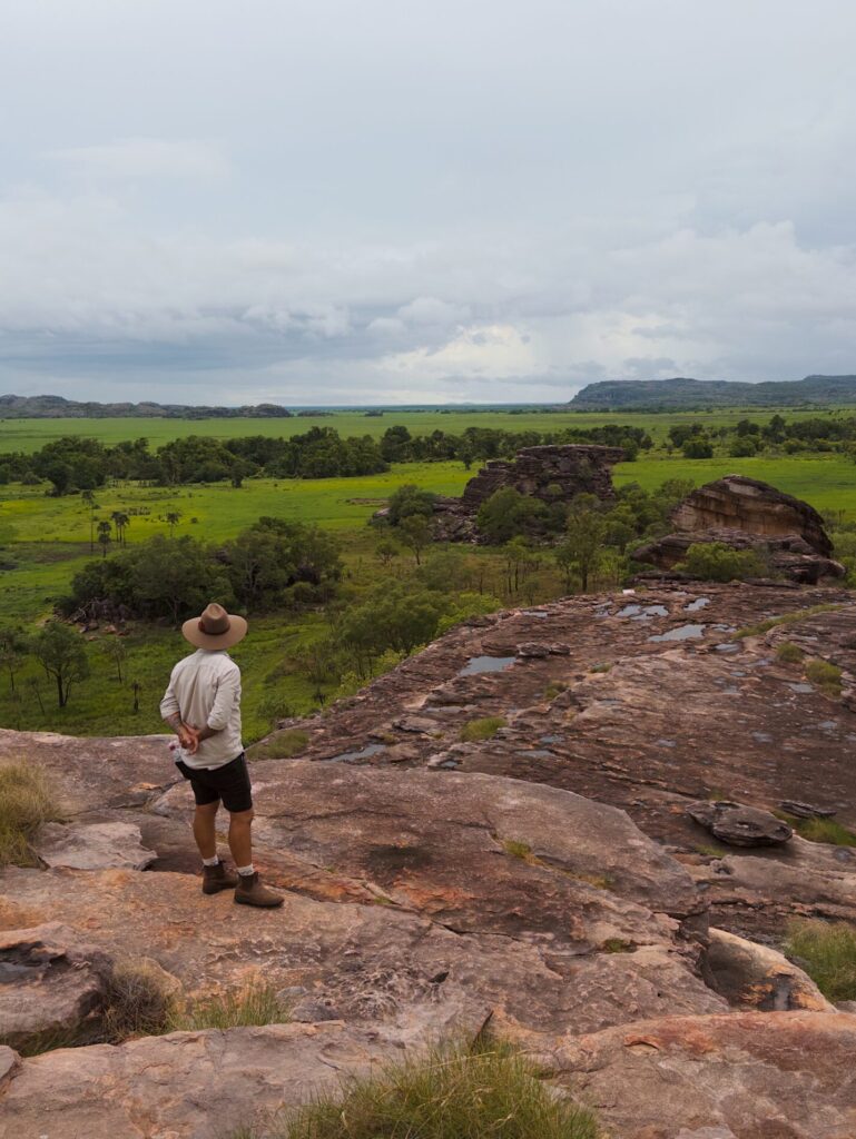 A man looking over a rocky and grassy landscape of Kakadu National Park, one of the top 10 things to do in Australia