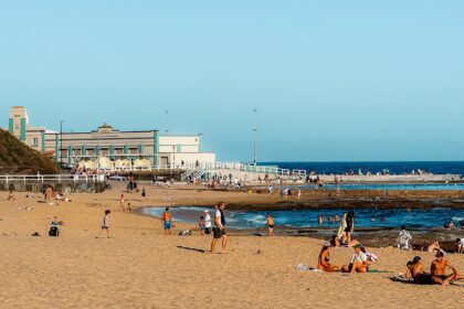 A yellow sand beach with people on it and some buildings in the distance - Brisbane to Sydney road trip