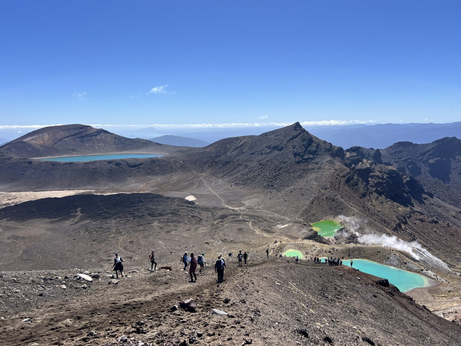 Turquoise pools nestled into the valley of a red rocky mountain outside of Taupo