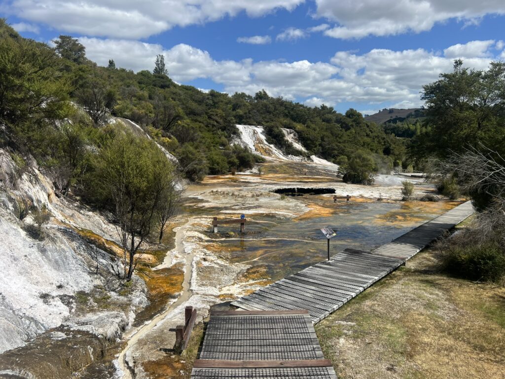The landscape of a geothermal area near the Tongariro Crossing with a boardwalk running over the orange and yellow rocks