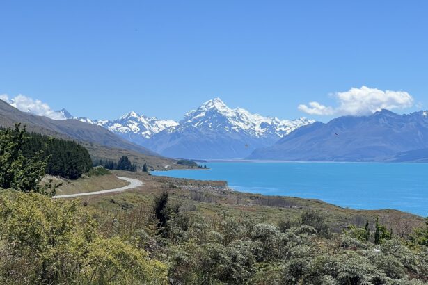 A teal blue lake beneath white-capped mountains on a trip from Christchurch to Dunedin