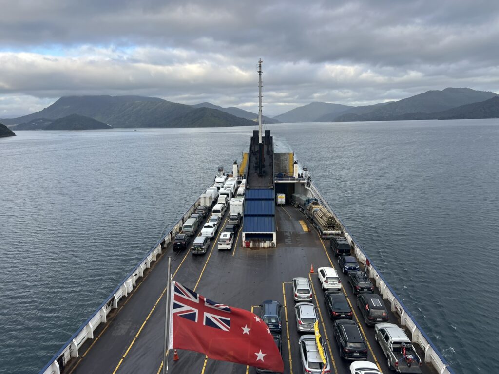 A ferry loaded with cars on top with land in the distance
