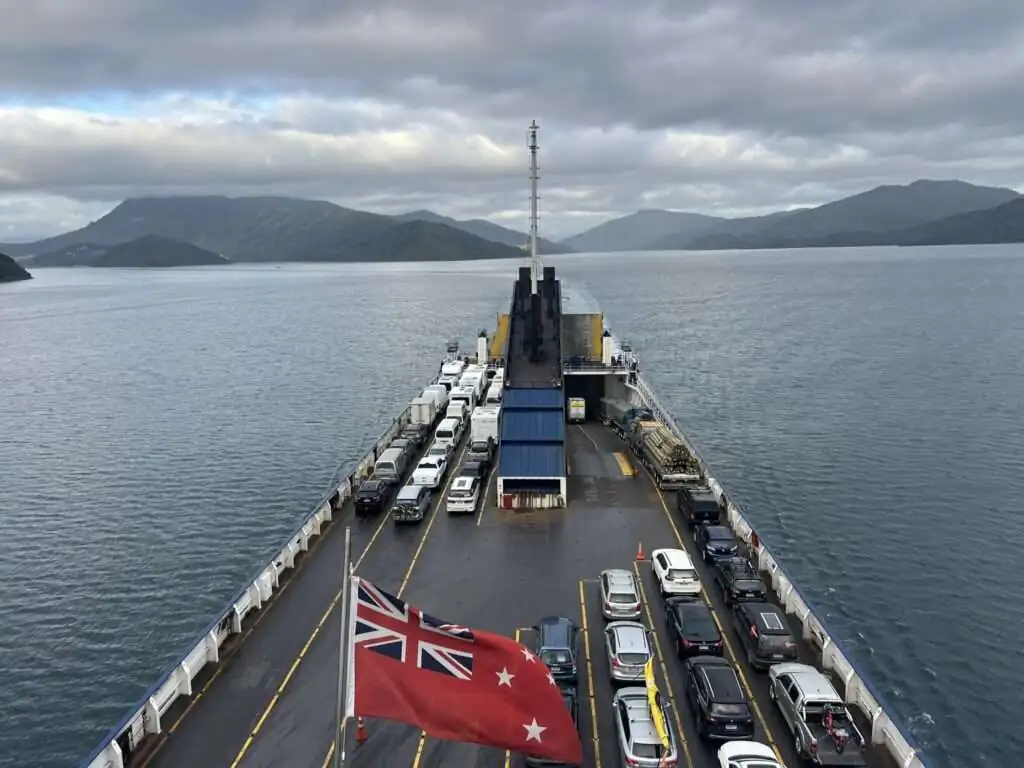 A ferry loaded with cars on top with land in the distance