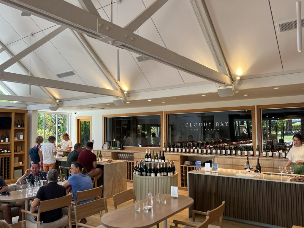 A wine tasting room with bottles and people sampling wine